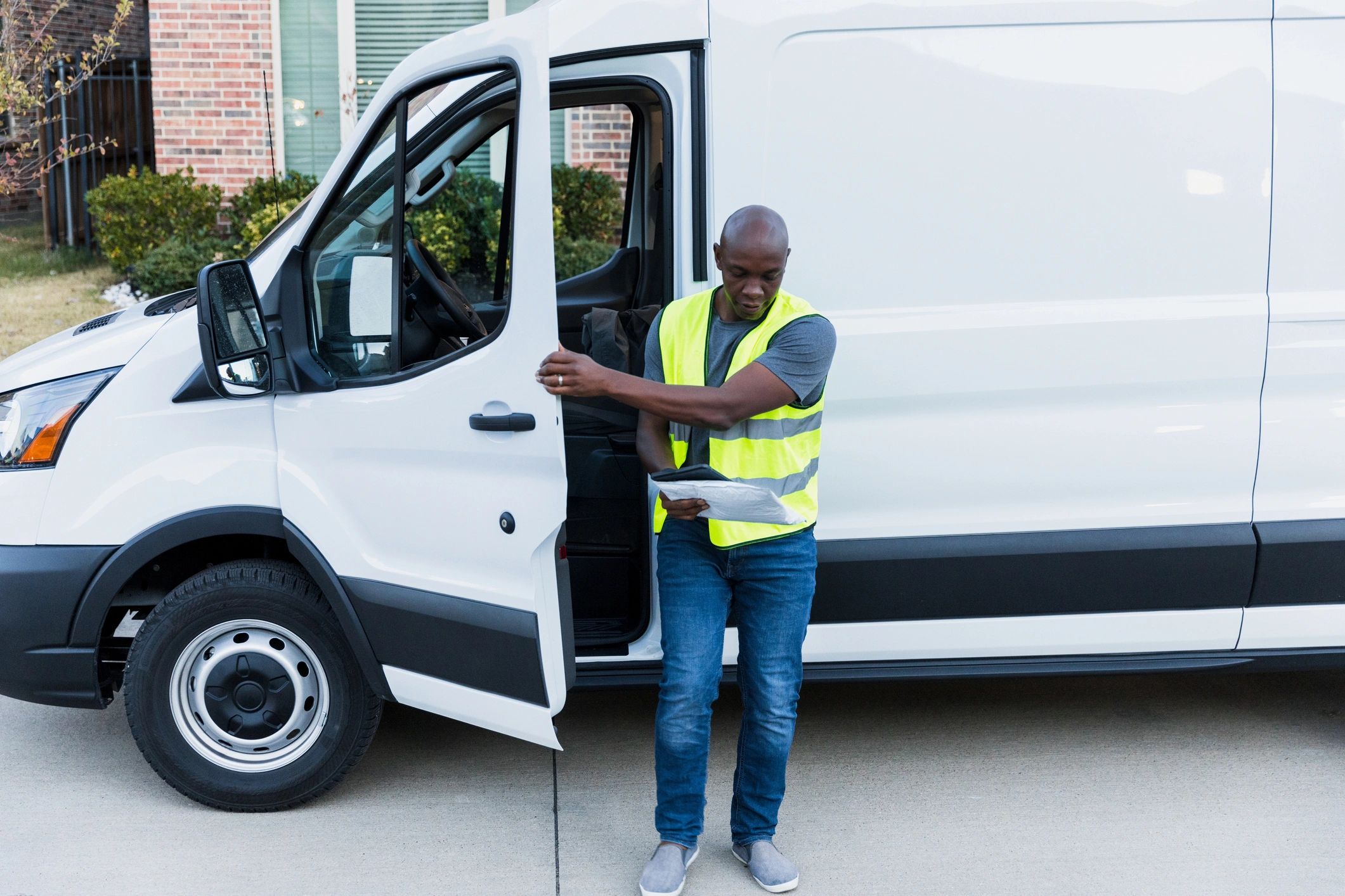 Driver looks at package while closing door of van