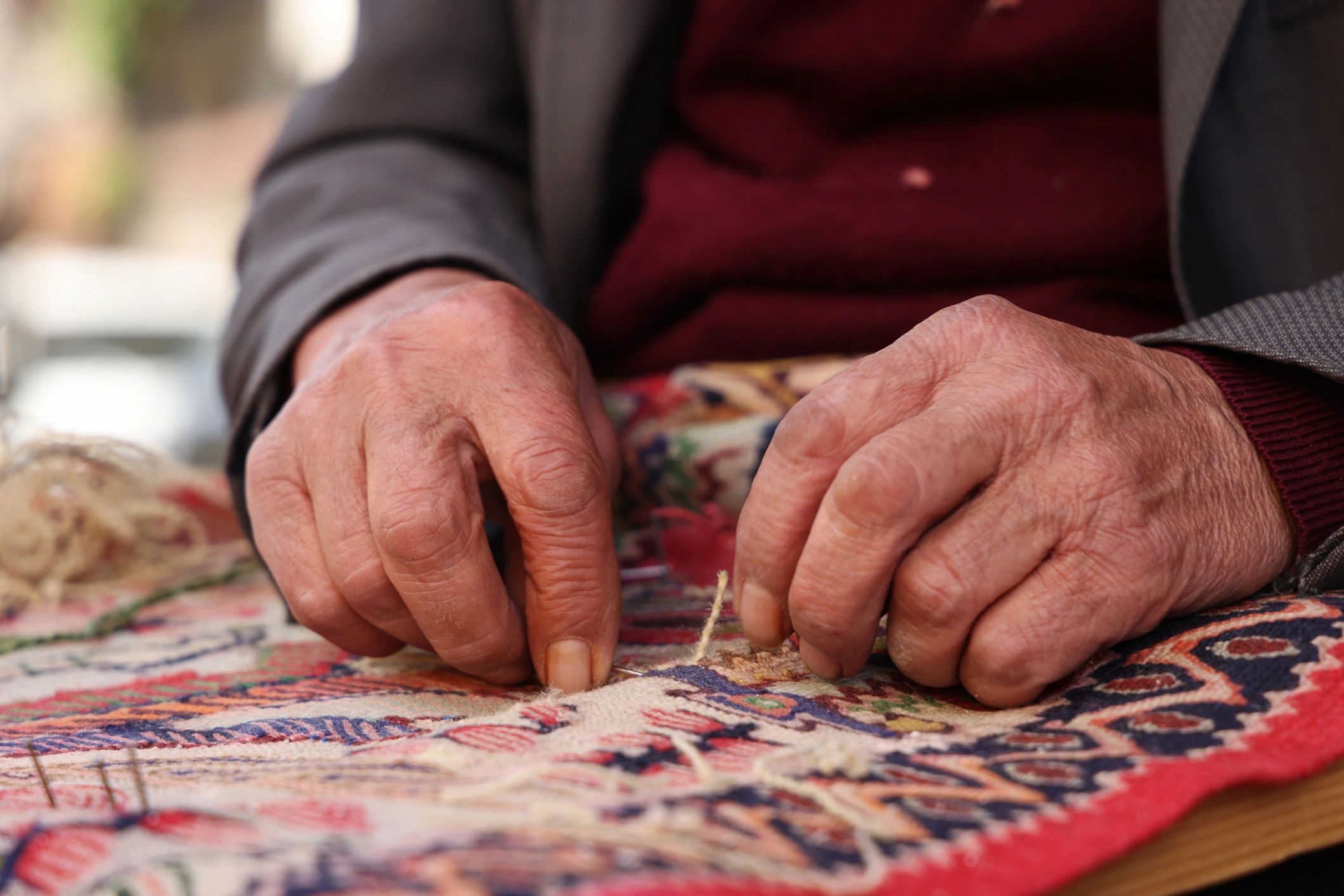 Artisan hand-sewing a rug in a workshop