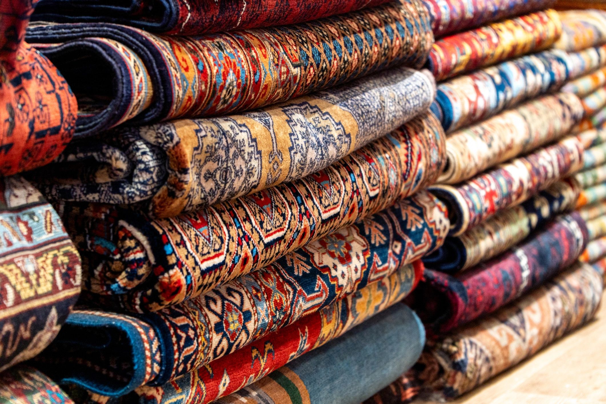 Stack of colorful traditional patterned rugs in a shop
